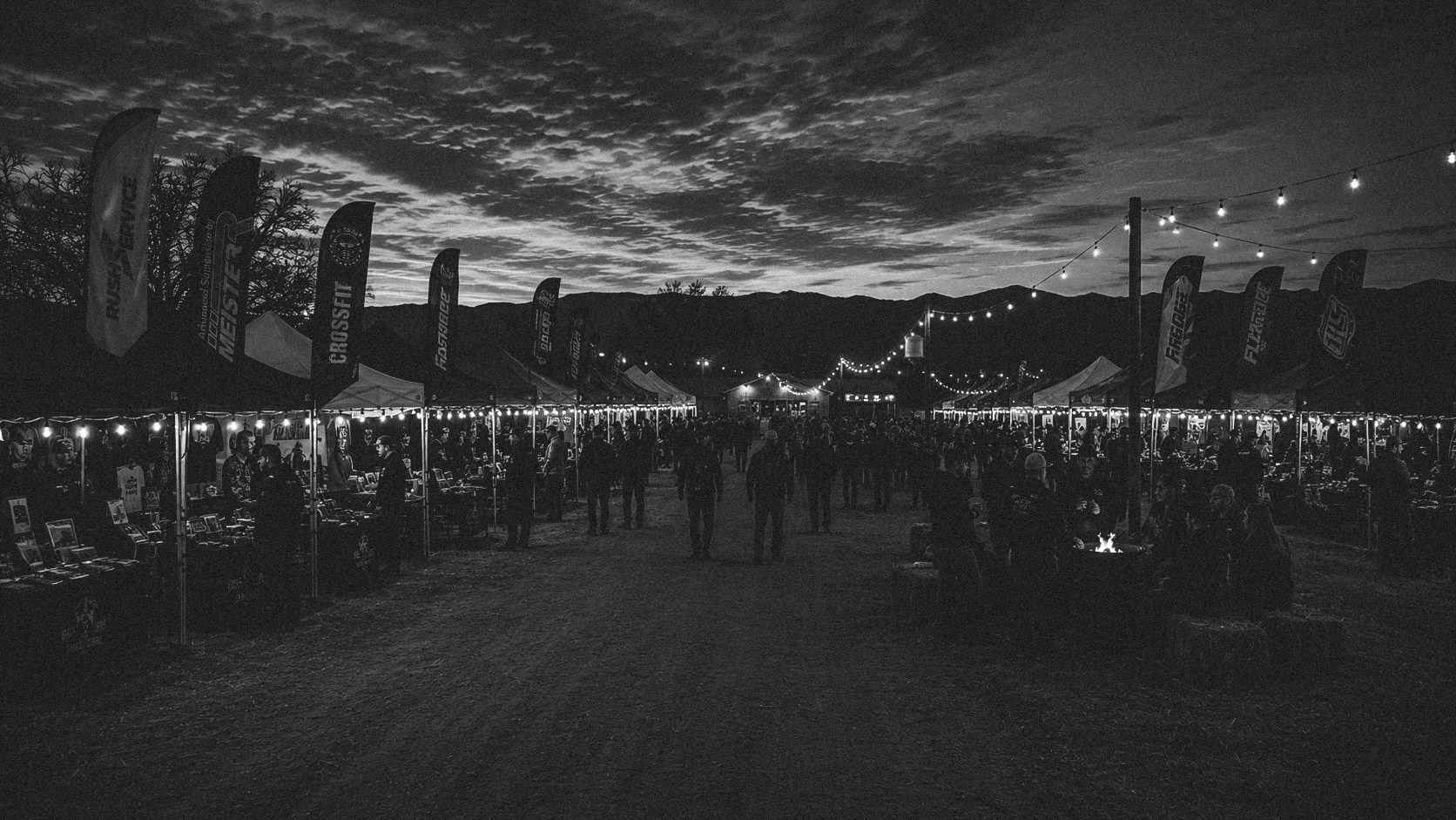 Festival vendor row beneath string lights at dusk.